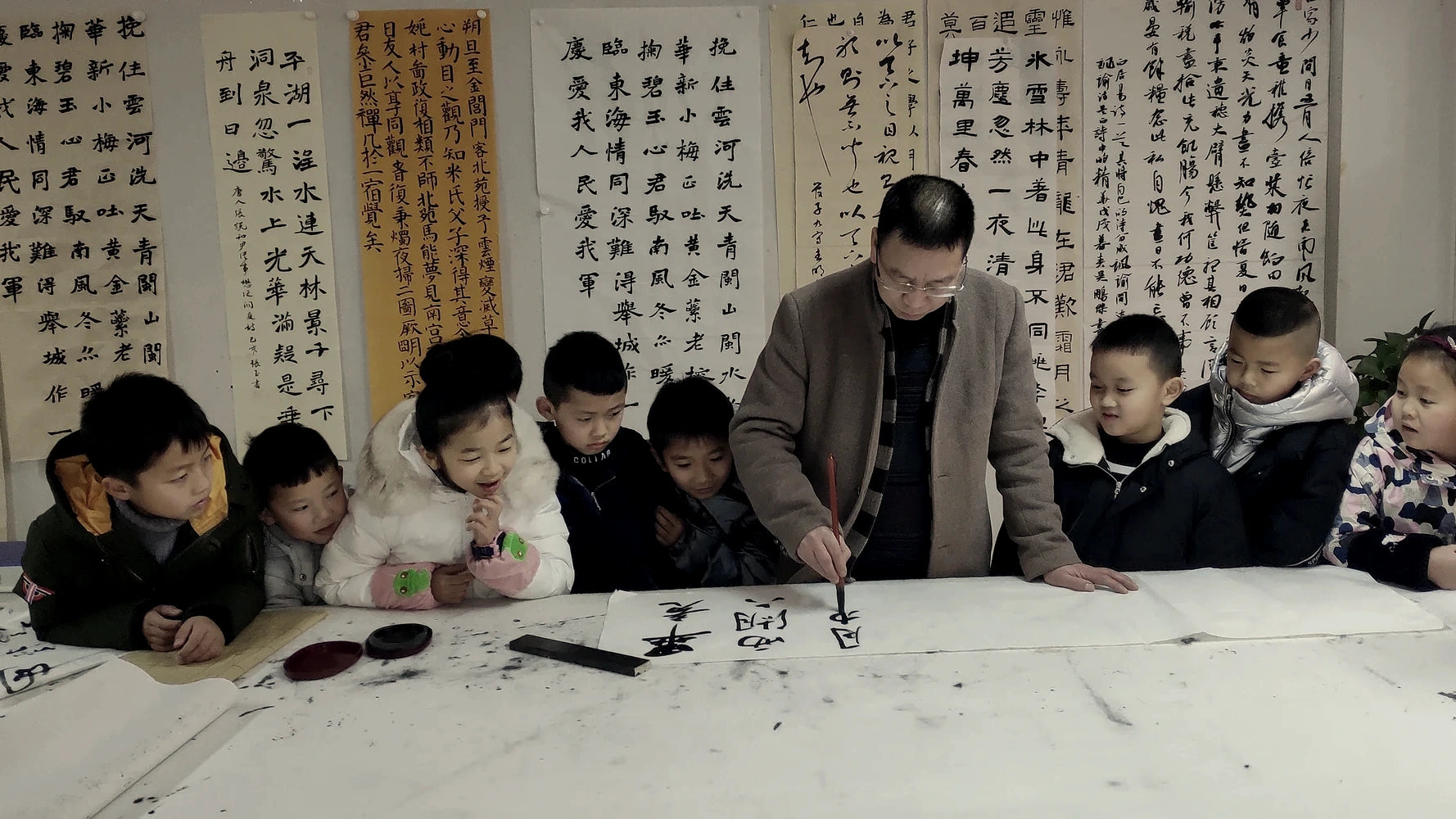 Artist Xu Hongke demonstrating Chinese calligraphy to a group of young students