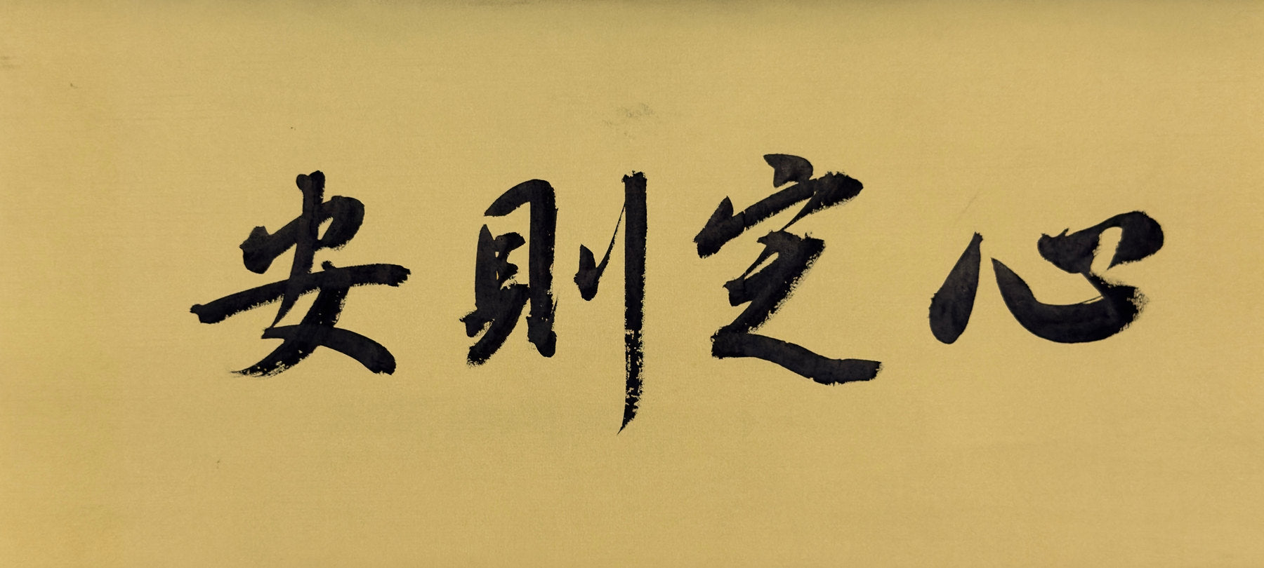 Second original: four characters handwritten in black ink on warm golden paper